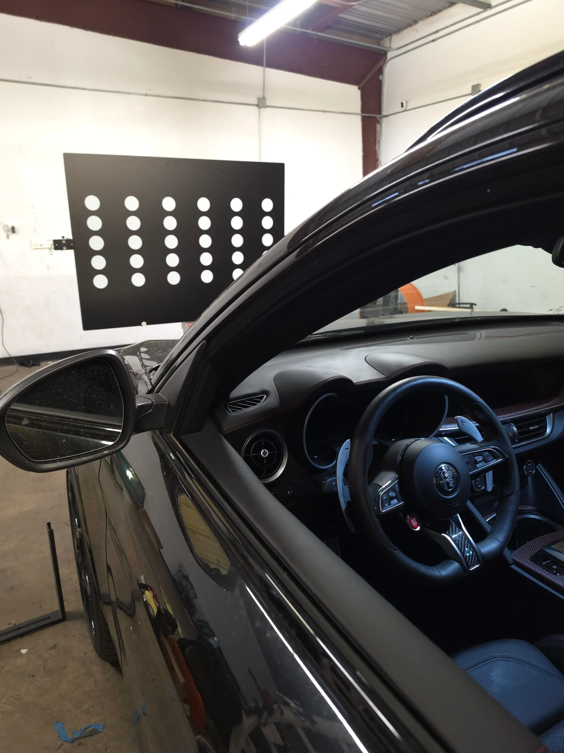 Alfa Romeo positioned at the ADAS calibration target board inside the A Star Auto Glass shop in Sarasota