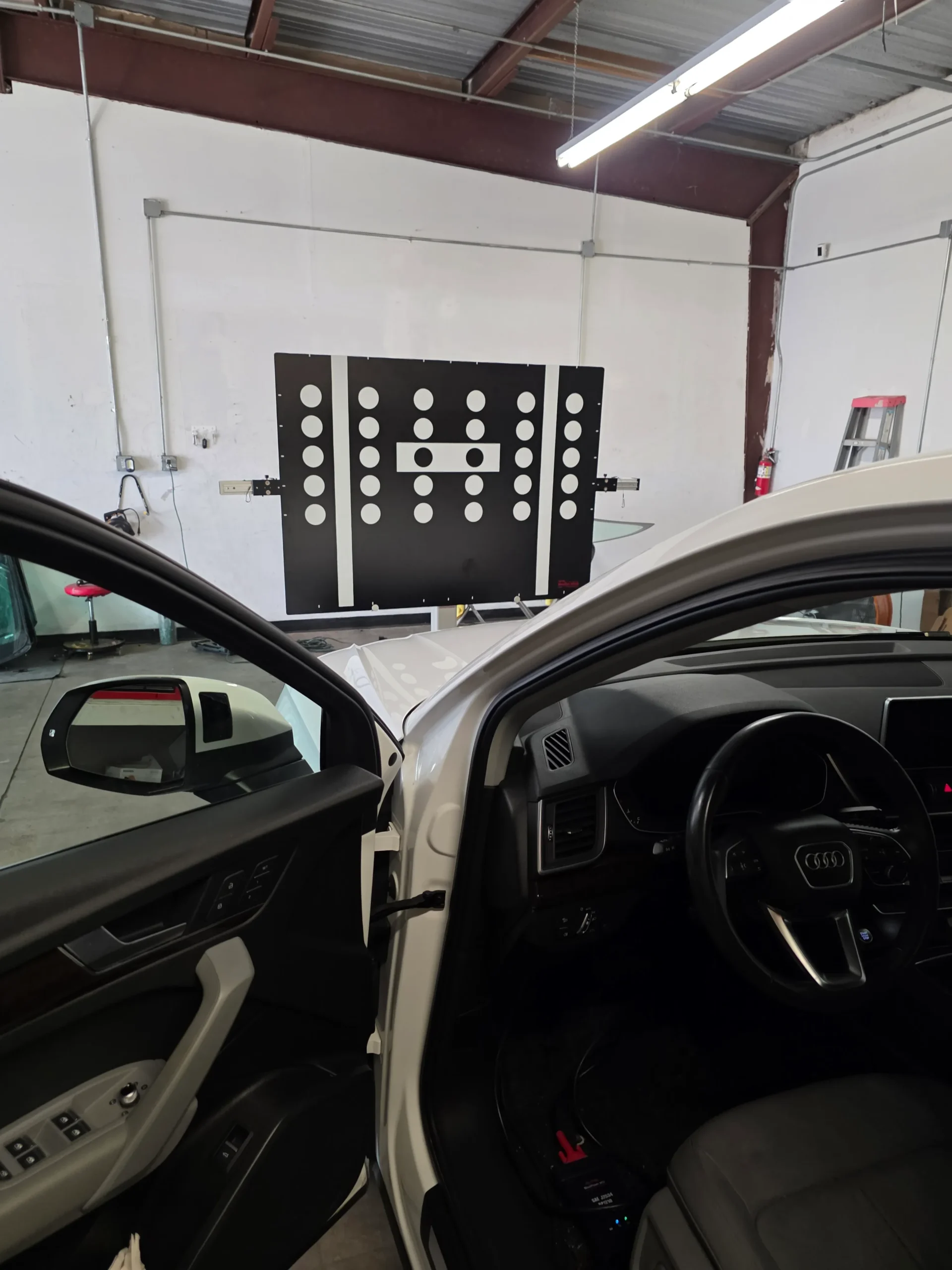 ADAS calibration target board in the A Star Auto Glass Sarasota shop, viewed from inside an Audi positioned for static calibration