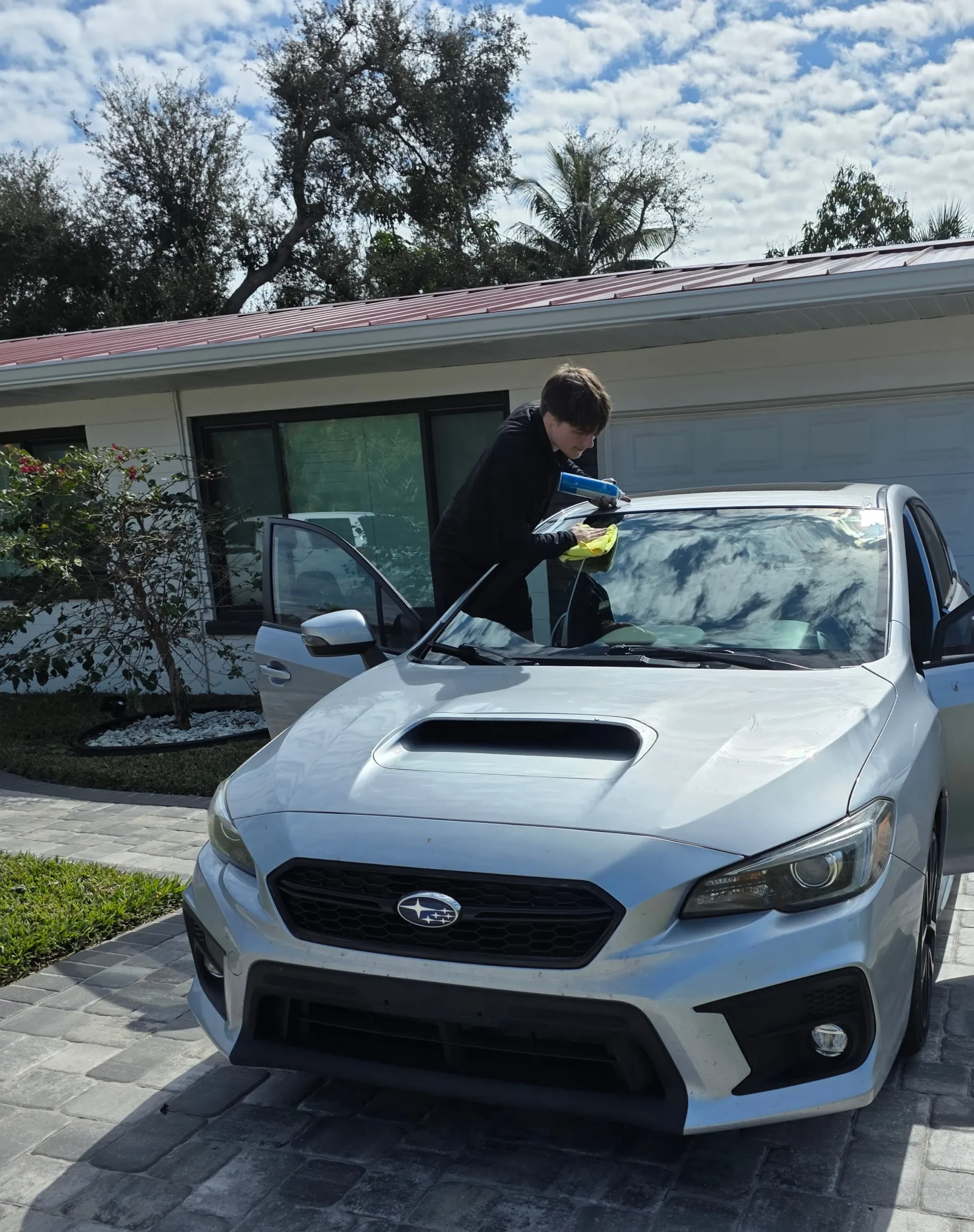 A Star Auto Glass technician installing a windshield on a Subaru WRX at a Sarasota FL home